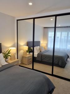a bedroom with two beds and a large mirror at Inner City 2 Bedroom Unit in Hamilton