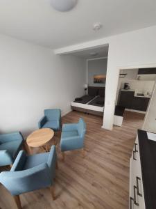 a living room with blue chairs and a table and a bed at Hafen Appartements Wismar in Wismar +64 photos
