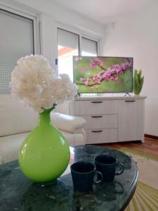 a green vase with flowers on a table in a living room at Apartment Andric 2 in Trebinje