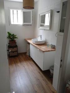 a bathroom with a white sink and a wooden floor at Maison au pays des lavandes et de la vigne in Pierrevert