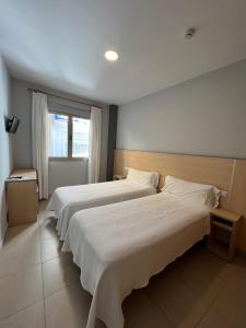 um quarto de hotel com duas camas e uma janela em Hostal Manuela em Punta Umbría