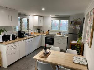 a kitchen with white cabinets and a wooden table at Goolwa Mariner’s Cottage - Free Wifi and Pet Friendly - Centrally located in Historic Region in Goolwa