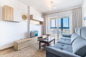 ein Wohnzimmer mit einem blauen Sofa und einem Tisch in der Unterkunft Acintur 11-A in Benidorm