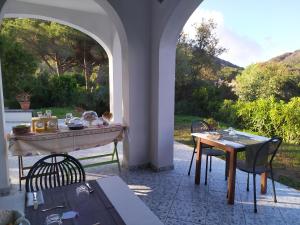 un tavolo e sedie in un patio con arco di B&B Casa Corbezzolo a Procchio