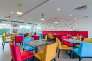uma sala de jantar com cadeiras e mesas coloridas em Ibis Styles Bucharest Airport em Otopeni