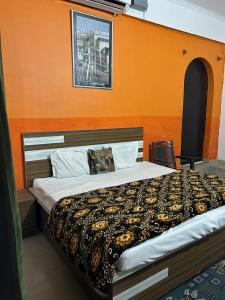 a bedroom with a large bed with an orange wall at Hotel Blue Star in Haldwāni