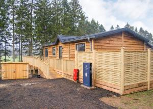 eine große Holzhütte mit einer großen Terrasse in der Unterkunft Thirlestane Woodland Lodges in Lauder