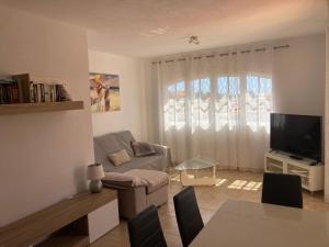a living room with a couch and a tv at Las Rocas Golf and Sea in Caleta De Fuste