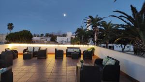 a row of chairs on a balcony with palm trees at Alojamiento Lo Trabucador in El Poblenou del Delta