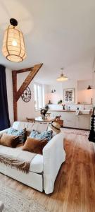 ein Wohnzimmer mit einem weißen Sofa und einer Küche in der Unterkunft Le Beffroi : appartement cosy en cœur de ville in Armentières