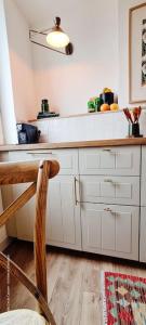 eine Küche mit weißen Schränken und einem Stuhl darin in der Unterkunft Le Beffroi : appartement cosy en cœur de ville in Armentières