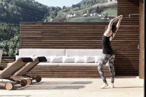 Eine Frau, die eine Yoga-Pose vor einer Couch macht. in der Unterkunft Hotel Schwarzschmied in Lana