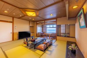 a living room with a table and chairs and a television at 銚子グランドホテル in Choshi