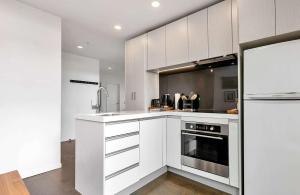 Una cocina con gabinetes blancos y un horno de estufa. en City and view holiday home, en Auckland
