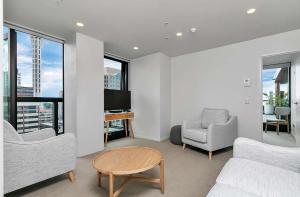 a living room with a couch and chairs and a tv at City and view holiday home in Auckland
