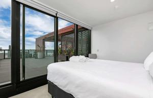 Un dormitorio con una cama blanca y un balcón. en City and view holiday home, en Auckland 24 fotos más