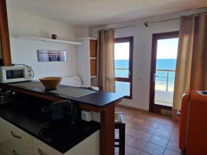 a kitchen with a counter with a microwave and a window at Apartamentos Wundermar in Torredembarra