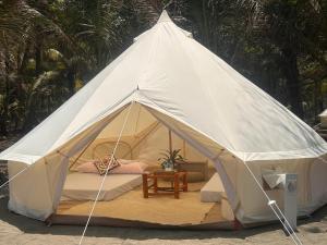een witte tent met een bed en een tafel bij INNBOX CAMPSITE in Bolinao