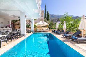 a pool with chairs and tables and umbrellas at Korsan Apartment No.5 in Kaş