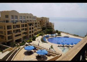 a view of a pool with blue umbrellas and buildings at Dead Sea view Elite apartment Samara Resort traveler award 2024 in Sowayma