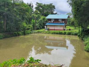 una casa e un laghetto di fronte a una casa di นาหินลาดรีสอร์ท Nahinlad Resort a Ban Khok Sawang (2)
