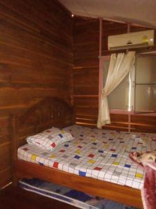 uma cama num quarto de madeira com uma janela em นาหินลาดรีสอร์ท Nahinlad Resort em Ban Khok Sawang (2)