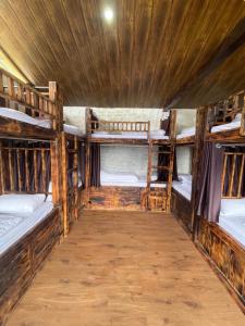 a room with three bunk beds and a wooden ceiling at Parvatis Lap Luxury Hostel & Camps in Kasol
