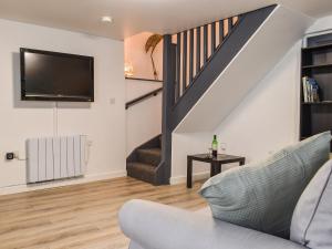 a living room with a couch and a tv and stairs at The Old Post House in Walton