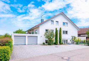 a white house with a garage on a driveway at Homebase bei Freiburg in March