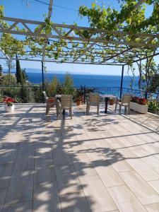a patio with chairs and a table with a view of the ocean at Ionian View Guest House in Qeparo