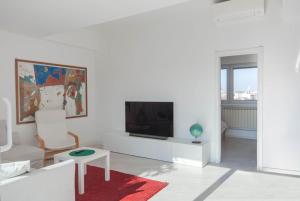 a white living room with a television and a red rug at Exclusive rooftop apartment with large terrace in Solari/Tortona in Milan