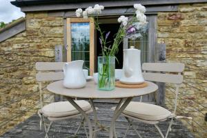 einen Tisch mit zwei weißen Vasen und Blumen darauf in der Unterkunft The Tallet - converted three bed stable - no children under 8 in Yeovil