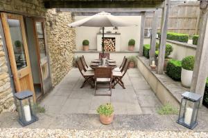 eine Terrasse mit einem Tisch und einem Sonnenschirm in der Unterkunft The Tallet - converted three bed stable - no children under 8 in Yeovil