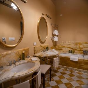 a bathroom with two sinks and a tub and a mirror at Albergo Pietrasanta in Pietrasanta