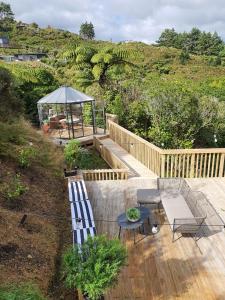 una terraza con 2 bancos, una mesa y una sombrilla en Tiny house with greenhouse dining en Lower Hutt