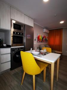 a kitchen with a white table and yellow chairs at Apartamento MS in Campo Maior