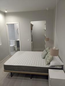 Cette chambre blanche comprend un grand lit et deux miroirs. dans l'établissement Apartamento Calle Concepción Pleno Centro, à Cordoue