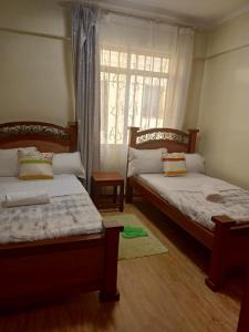 sypialnia z 2 łóżkami i oknem w obiekcie Lux Suites Skyhorse Apartments Kilimani w mieście Nairobi