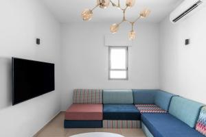 a living room with a blue couch and a flat screen tv at The Beach House in Nahariyya