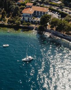un barco en un cuerpo de agua con una casa en Hotel Villa Maria Au Lac - Estella Hotels Italia, en Toscolano Maderno