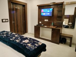 un soggiorno con TV e un letto in una camera di StudioZ Paradise Hills Mussoorie a Mussoorie