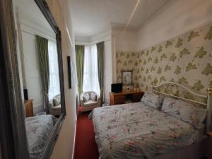 1 dormitorio con cama y espejo en Florence Guest House, en Weston-super-Mare