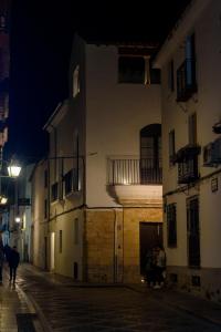 een groep mensen die 's nachts over straat lopen bij Casa del Cardenal in Córdoba