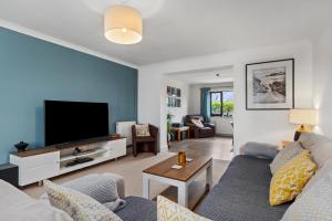 a living room with a couch and a flat screen tv at Woodfield House - Beautiful Tenby Cottage in Tenby