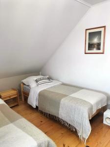 two beds in a room with white walls and wooden floors at Domek Aga in Węgorzewo