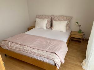una camera da letto con un letto grande con lenzuola e cuscini bianchi di Haus Elke a Hard