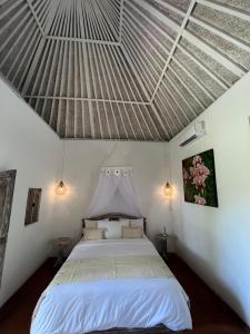 a bedroom with a white bed with a metal ceiling at Alamanda Bingin in Uluwatu