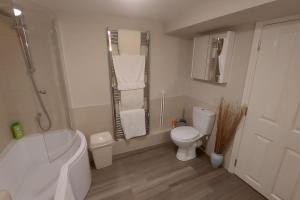 a bathroom with a tub and a toilet and a sink at The Den, 2 mins Chelt High Street, John Lewis etc in Cheltenham +3 photos