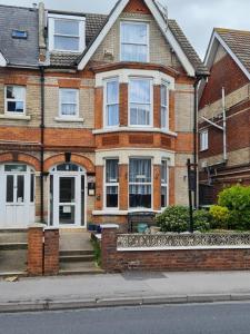 a brick house with a white door on a street at Marden guest house in Weymouth