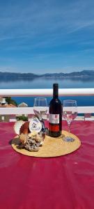 a bottle of wine and two wine glasses on a table at Apartmani ANCORA, Crkvice in Kuna Pelješka